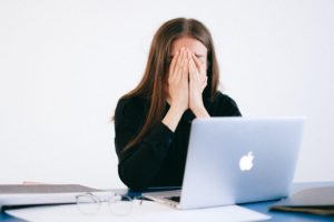 mujer sentada en su mesa de trabajo con el ordenador sufriendo una crisis de ansiedad laboral