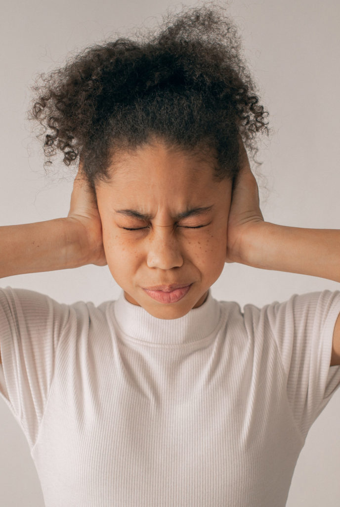 mujer con las manos en los oídos sufriendo un ataque de ansiedad social