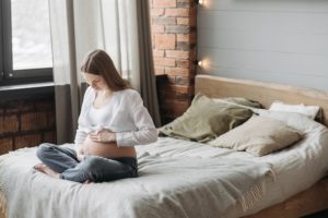 imagen de una chica embaraza sentada en la cama sufriendo ansiedad por cambios en la salud mental durante el periodo perinatal 